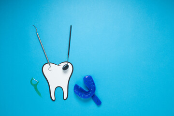 White fake tooth with dental instruments, light blue background. Dentist's Day, dental health