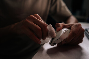 Man cleaning computer mouse with disposable wipe, emphasizing hygiene and sanitation for workspace...