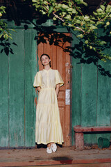 Naklejka premium Woman yellow dress wooden door green wall sunlight, authentic inclusive