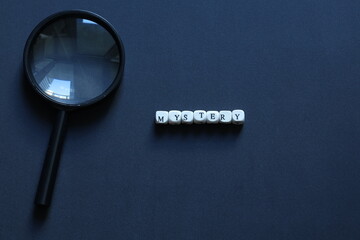 Minimal conceptual image of the word mystery spelled with letter tiles on dark background, symbolizing secrets, curiosity, investigation, and the unknown.