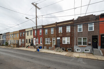 Obraz premium Street level view of a road and a long line of rowhouses without cars in a South Philadelphia neighborhood, Pennsylvania, USA
