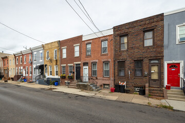 Naklejka premium Street level view of a road and a long line of rowhouses without cars in a South Philadelphia neighborhood, Pennsylvania, USA