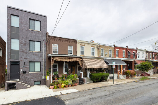 Street level view of a road and a long line of rowhouses without cars in a South Philadelphia neighborhood, Pennsylvania, USA