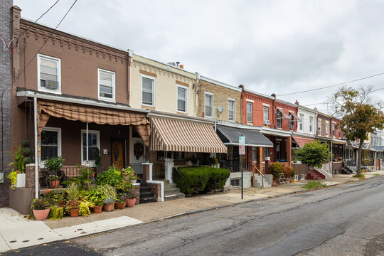 Street level view of a road and a long line of rowhouses without cars in a South Philadelphia neighborhood, Pennsylvania, USA