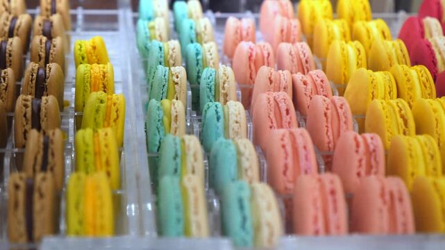 Rows of vibrant and delicious macarons in various flavors and colors beautifully arranged in a bakery display case, showcasing the delicate and classic french almond meringue confection