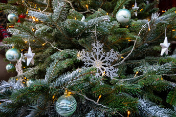Natural spruce branches decorated with festive silver snowflake on the Christmas tree.
