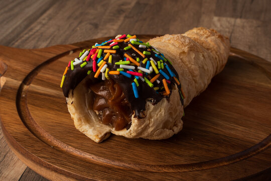Cucurucho de hojaldre relleno de manjar con cobertura de chocolate