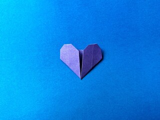 Single origami heart on a blue background representing calm emotions and inner harmony