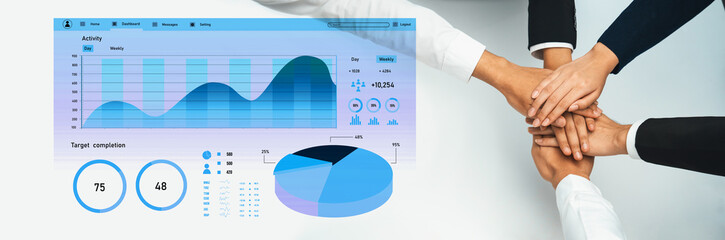 A diverse business team collaborates by joining hands around charts and graphs, displaying data analysis and performance metrics for effective project management. Axiom