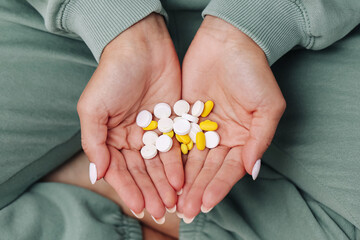 Hands holding assorted pills and tablets. Daily medication dosage concept. Healthcare routine and treatment planning. Prescription and supplements in human palms. Medical therapy and health management