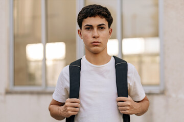 Teenage student with backpack looking at camera outdoors
