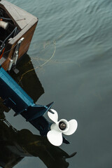 Close-up of an outboard motor propeller in calm water attached to a small boat