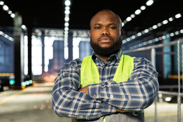 Black engineer at a worksite monitoring machinery automation, highlighting steel fabrication,...