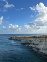 White Coastal Cliffs Above Calm Blue Sea Under Cloudy Sky.
White rocky sea cliffs above calm blue ocean water with dramatic clouds and wide copy space.