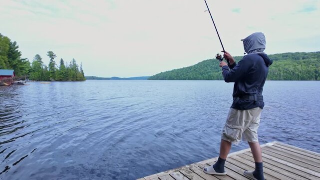 Man using finesse fishing angling style technique with light tackle rod, line, and lure with bobber. Angler setting the hook or hooking the fish during summer vacation fishing.