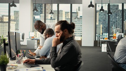 Corporate coworkers engaged in task management and completion. Employees discuss metrics, market research and report writing to support strategy and professional development.