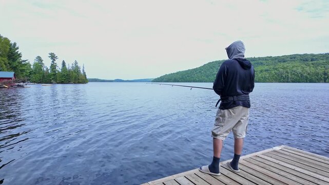 Man using finesse fishing angling style technique with light tackle rod, line, and lure with bobber. Angler setting the hook or hooking the fish during summer vacation fishing.