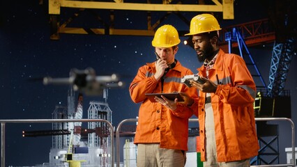 Diverse experts using aerial photography for offshore oil rig during drone survey, supporting...