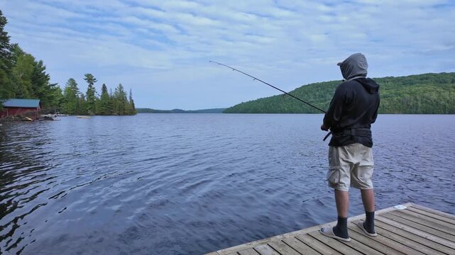 Man using finesse fishing angling style technique with light tackle rod, line, and lure with bobber. Angler setting the hook or hooking the fish during summer vacation fishing.