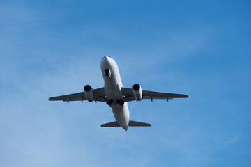 Obraz premium White commercial airplane climbing in clear blue sky after takeoff. White plane climbing after takeoff against the blue sky