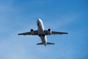 Fototapeta premium White commercial airplane climbing in clear blue sky after takeoff. White plane climbing after takeoff against the blue sky