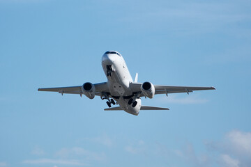 Obraz premium White commercial airplane climbing in clear blue sky after takeoff. White plane climbing after takeoff against the blue sky