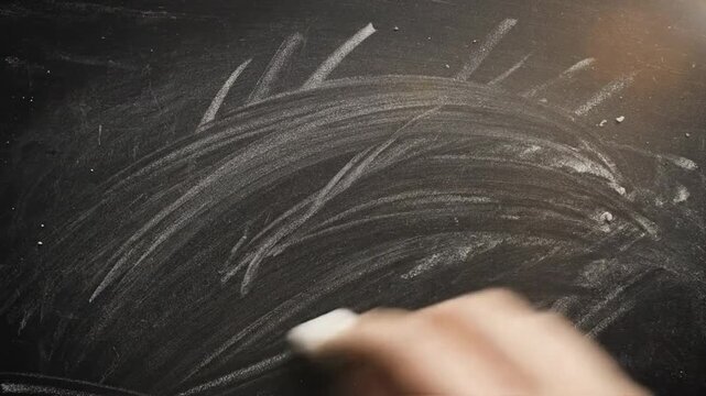 Hand drawing with chalk on black chalkboard surface creating texture and abstract shapes with detail close up