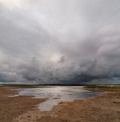 Storm clouds forming over a beach with the tide rising and sea encroaching 