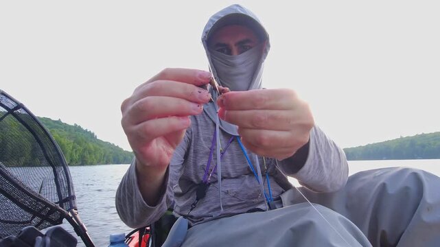 Angler put night crawler bait on fishing hook, drop shot fishing technique. Kayak sport fishing. Angler enjoys kayak fishing at scenic coastline. Peaceful water setting at lake Simcoe, Ontario, Canada