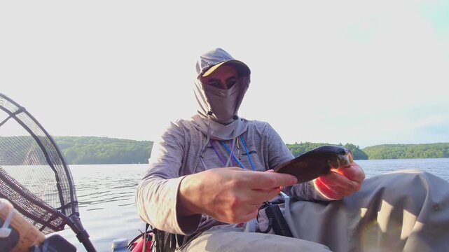 Kayak fishing solitude at lake Simcoe in Ontario, Canada, surrounded by stunning nature and tranquility. Angler enjoys solitude during hot summer evening. Man casts and reels his spinning rod.