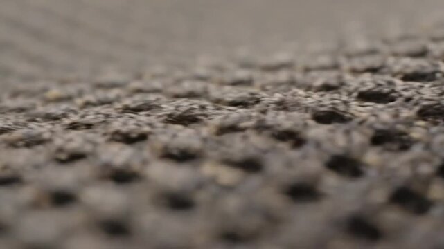 Extreme close-up macro view of porous fabric texture with dimpled holes and detailed fibers in a neutral color.
