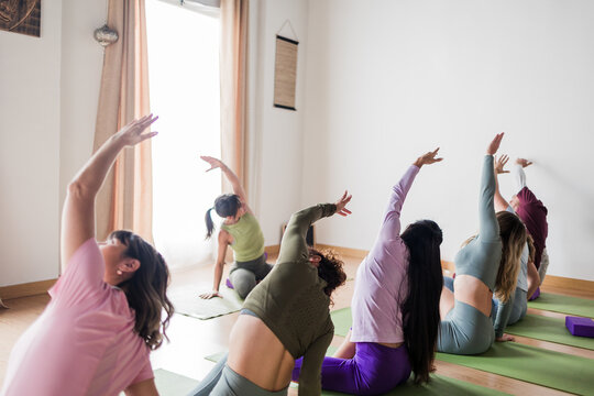 Multicultural women practicing yoga vinyasa in studio - Powered by Adobe