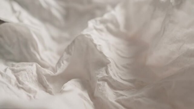 Close up view of crinkled white tissue paper surface with delicate texture and soft lighting, creating a minimalist background