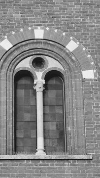 Black and white architectural detail of a medieval bifora window with a central column