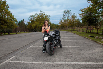 Obraz premium Woman biker standing with sportbike in parking lot