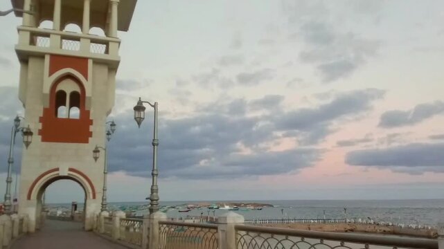 This is Bridge 45. The bridge has a pedestrian walkway. A great view of the sky, the Mediterranean Sea, Al-Kour Island (Miami Island) and boats is behind the bridge. The view is near the sunrise.