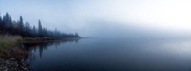Naklejka premium Panorama of a foggy morning at a northern lake with the sky fading to transparent 