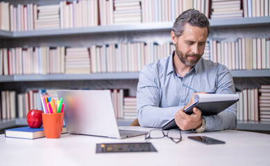 Teacher in classroom. school tutor in classroom. Man on lesson in class. teachers day. man tutor preparing for school exam. tutor making notes at lesson. teaching school subject. love for learning