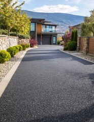 Modern home with a long, dark driveway leading towards a two-car garage