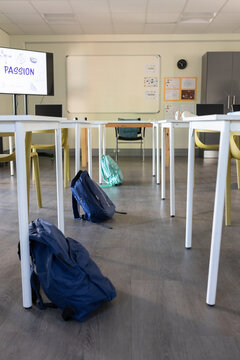 Navy backpack is sitting on aisle between white tables and yellow chairs, PASSION display at front