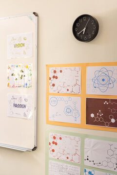 Whiteboard showing VISION and PASSION while lab posters showing chem diagrams and clock ticking