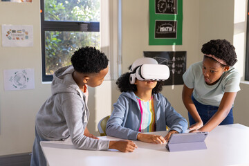 African American teens in class using VR headset, center girl wearing hoodie, using tablet