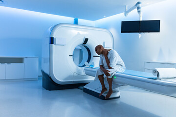 Circular medical scanner glowing with blue light and motor table sliding forward in radiology room