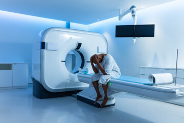 CT scanner gantry dominating left side and motorized exam table extending right with blue LEDs