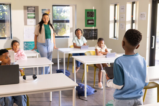 African American teacher with students leading lesson in classroom, boy holding tablet, copy space