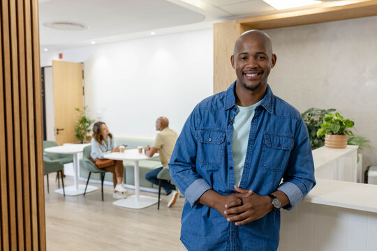 African American coworkers chatting in office lounge, man wearing denim shirt and wristwatch