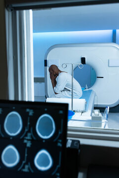 CT gantry is glowing with blue accent lighting in scanner bay, monitor displaying axial head scans