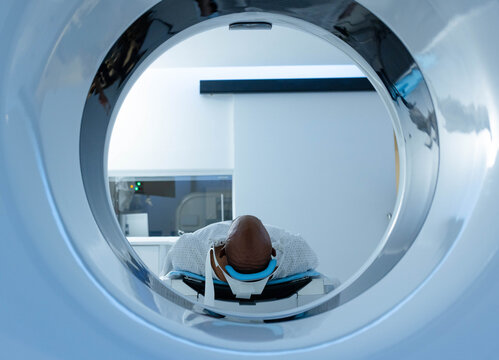 Scanner bore framing patient supine on motorized table in radiology room, showing blue head coil