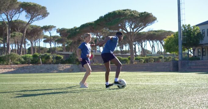 Teenage teammates starting 1v1 drill on turf dribbling and shielding soccer ball for possession