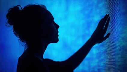 Silhouette of a woman reaching and touching a blue glowing screen, symbolizing modern technology, communication, and connectivity